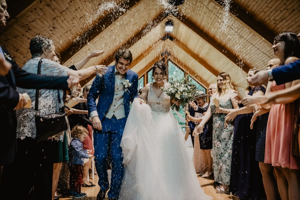 Bride and Groom with confetti thrown over them by Wedding Guests